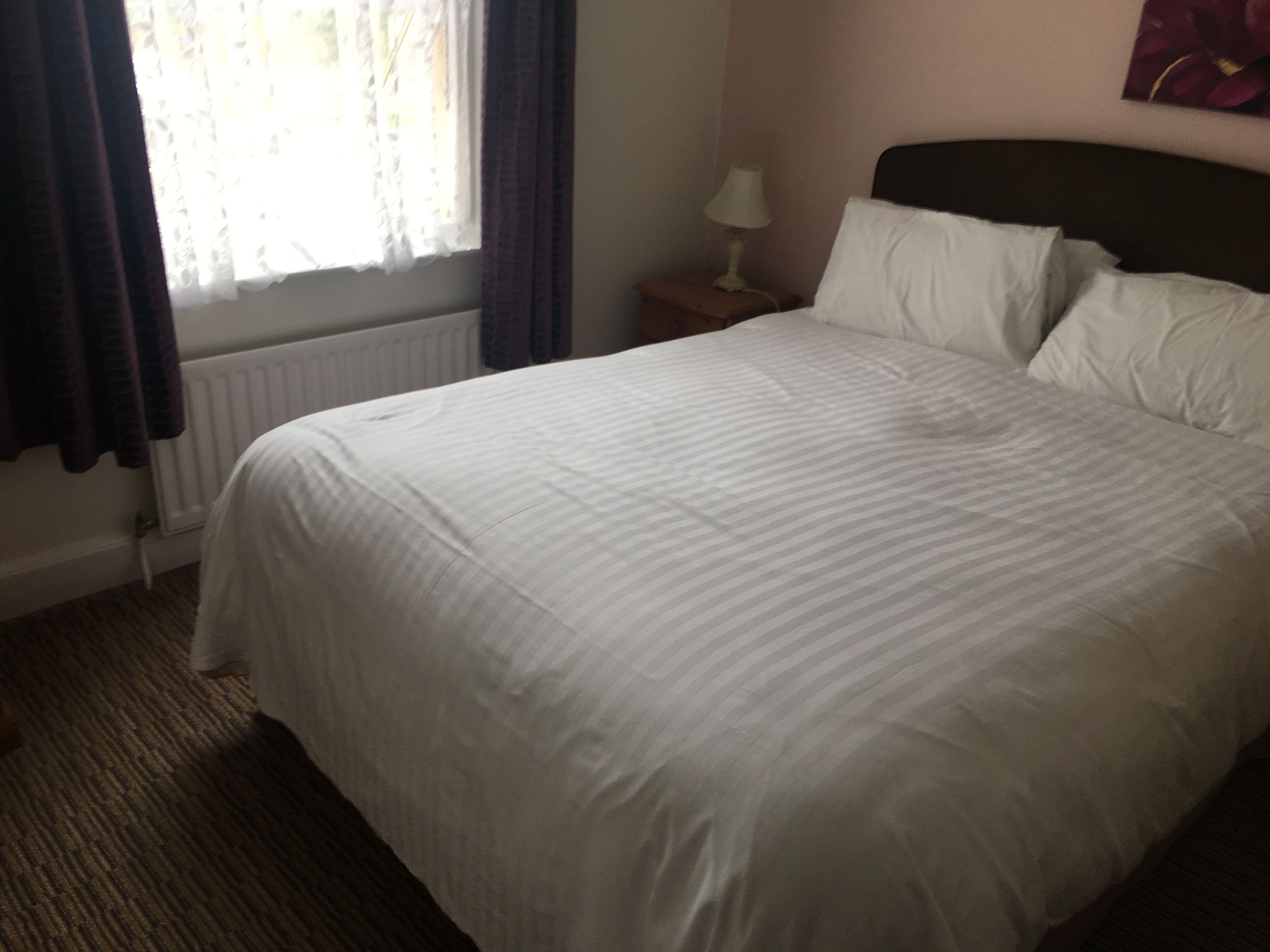 Un lit bien fait, avec du linge de lit blanc, dans une chambre d'hôtel.