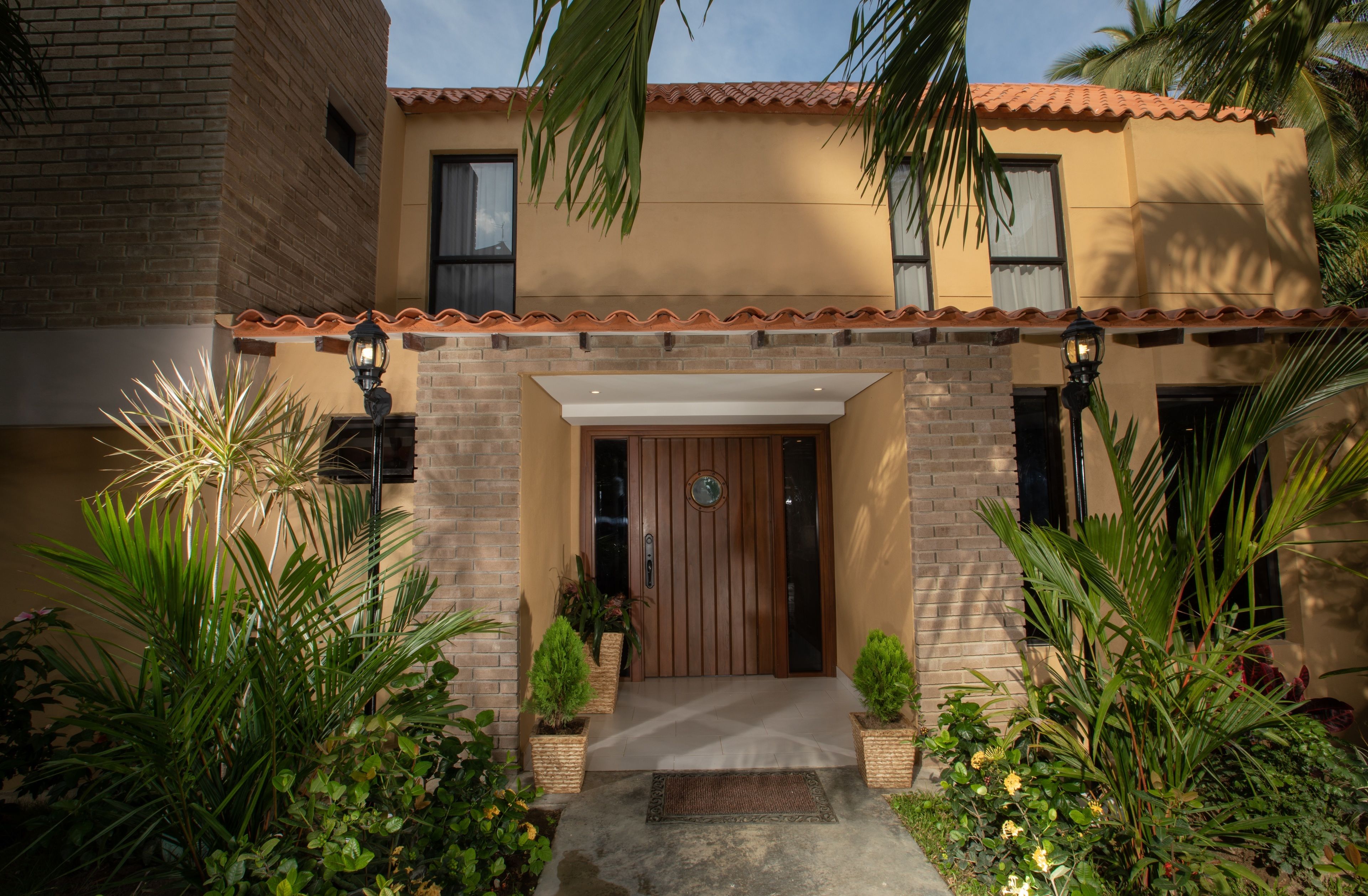 A two-story building with a brick facade, a tiled roof, and a wooden front door.