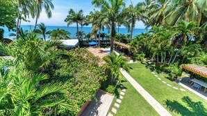 A tropical resort with a pool area, palm trees, and a view of the ocean.