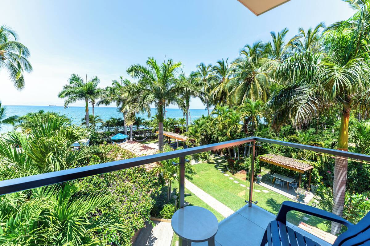 Un balcon donnant sur un jardin tropical et l’océan.