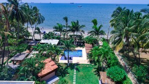 A resort with a swimming pool, palm trees, and a view of the ocean.