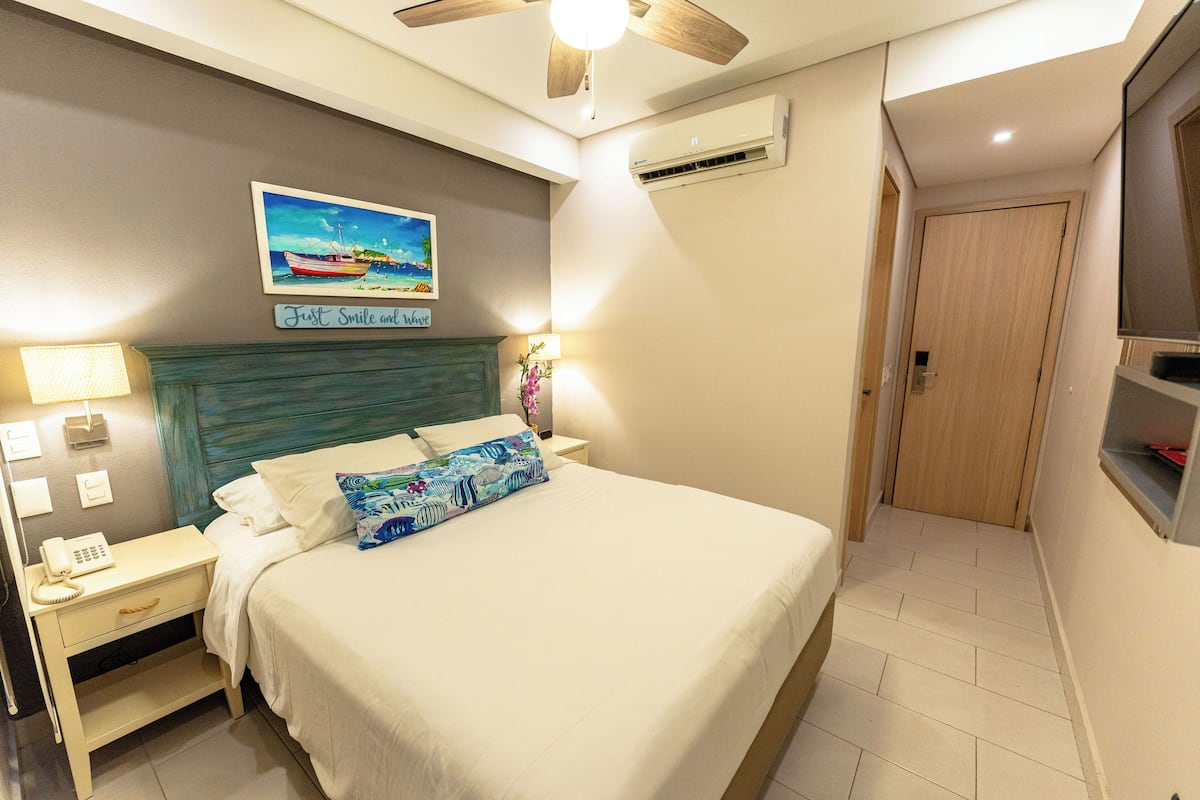 Une chambre d’hôtel bien rangée, avec un lit, une table de chevet, une lampe et un tableau au mur.