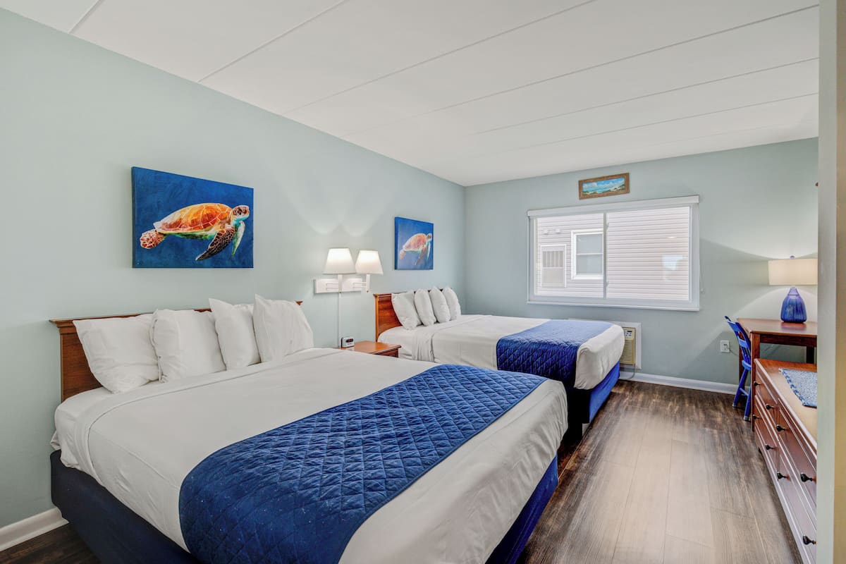 Habitación de hotel con dos camas, un escritorio y una ventana con persianas.