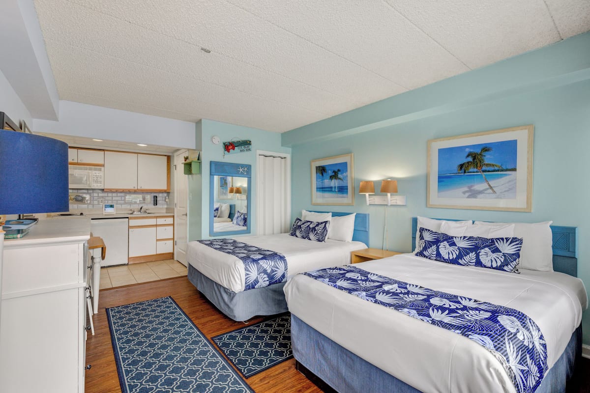Una habitación de hotel con dos camas, kitchenette y baño.