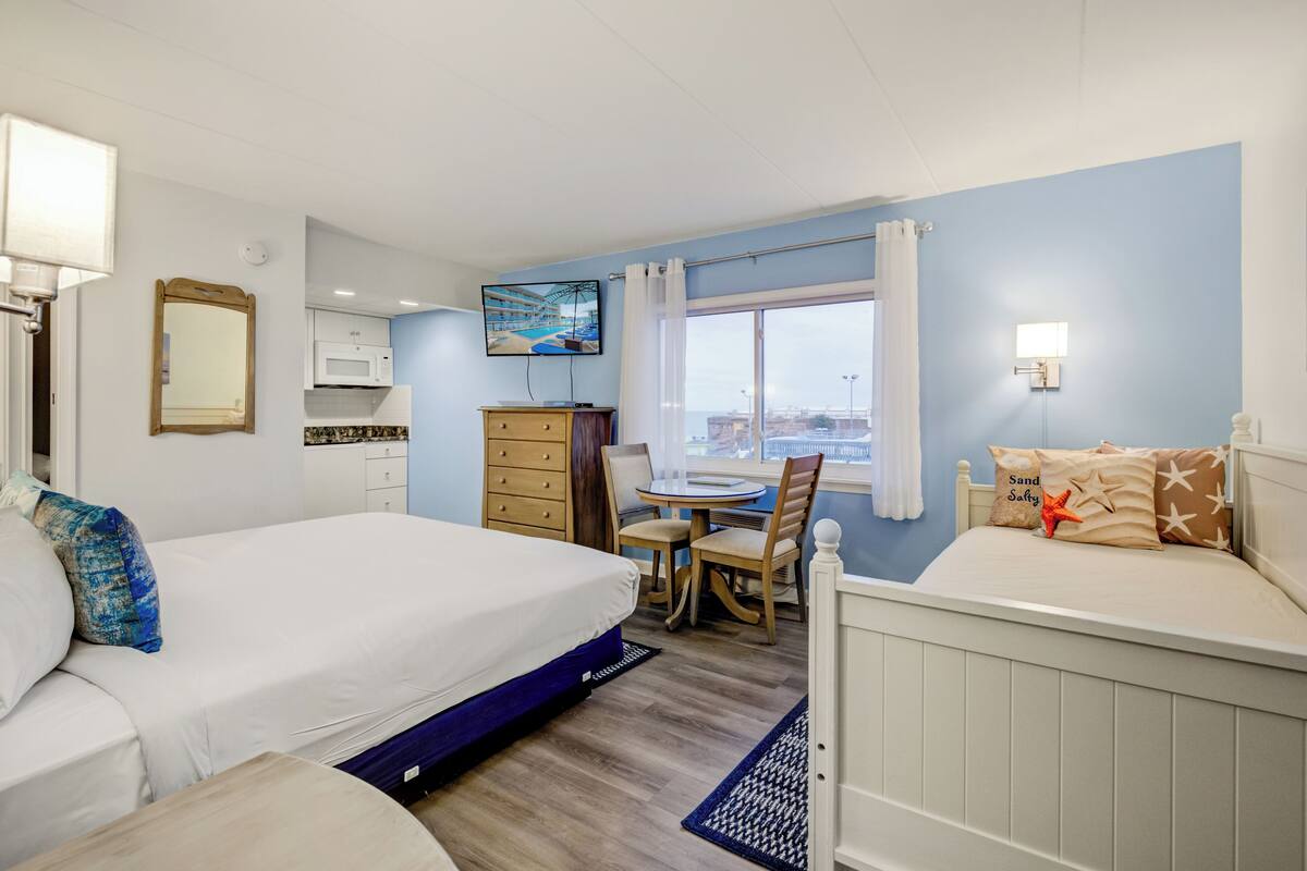 Habitación de hotel con cama, escritorio, silla, televisor y ventana con vistas.