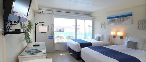 Ein Hotelzimmer mit zwei Betten, einem Schreibtisch, einem Fernseher und einem Balkon mit Blick.