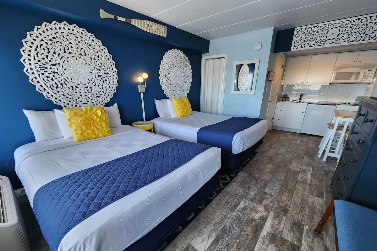Habitación de hotel con dos camas, kitchenette y decoración mural.