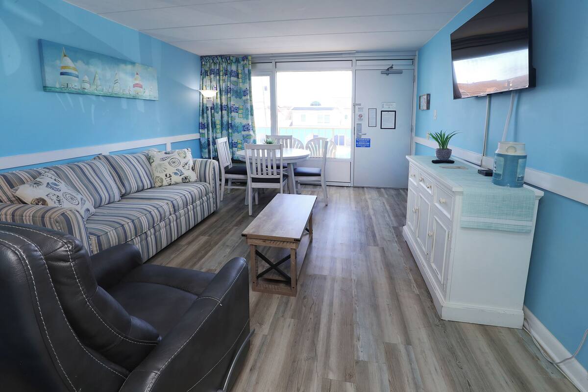 Una sala de estar con sofá, mesa de centro, televisor y balcón con vistas.