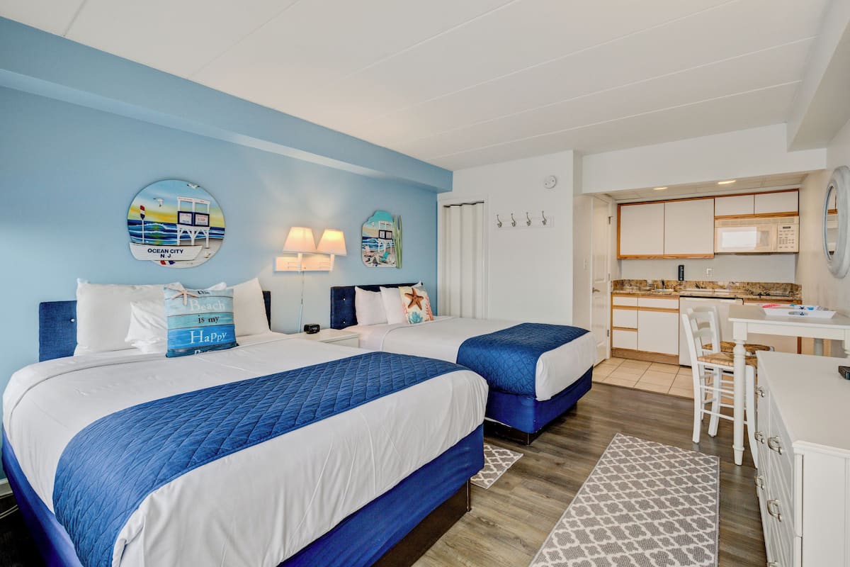 Habitación de hotel con dos camas, kitchenette y baño.