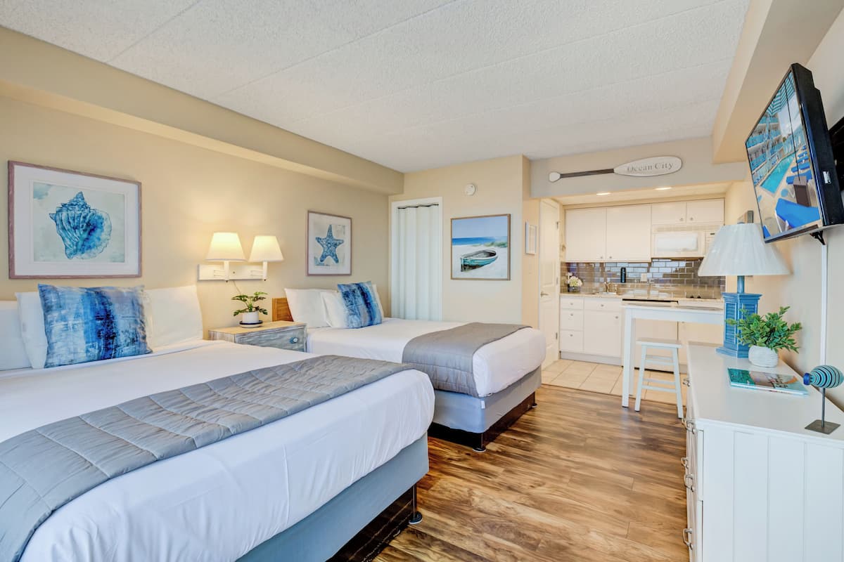 Habitación de hotel con dos camas, un escritorio y una kitchenette.