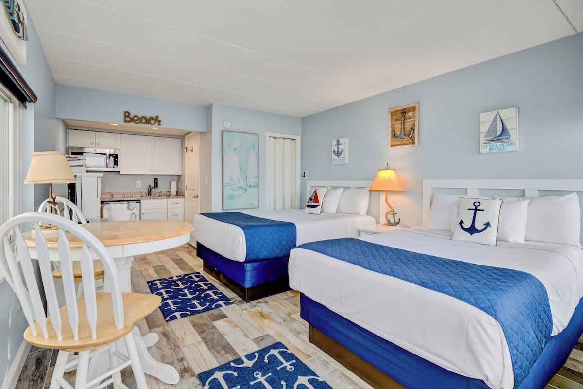 Habitación de hotel con dos camas, un comedor y decoración temática náutica.