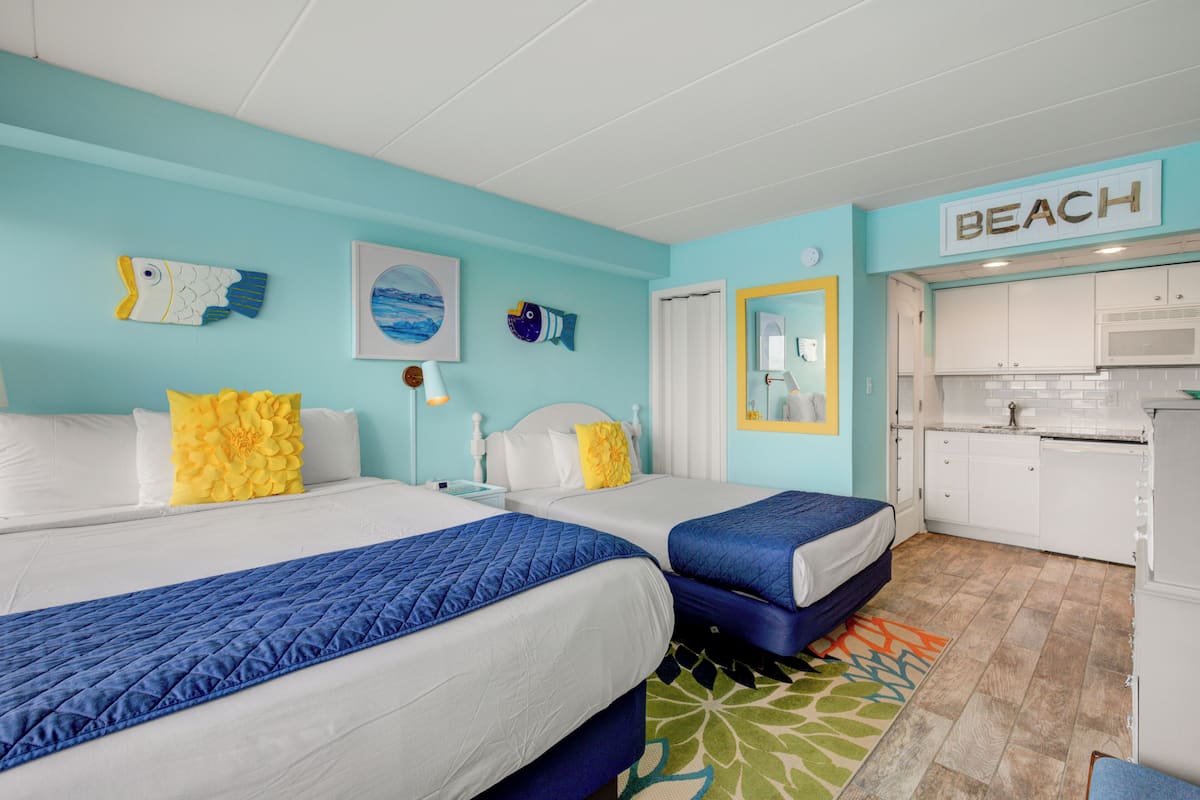 Una habitación de hotel con dos camas, kitchenette y baño.