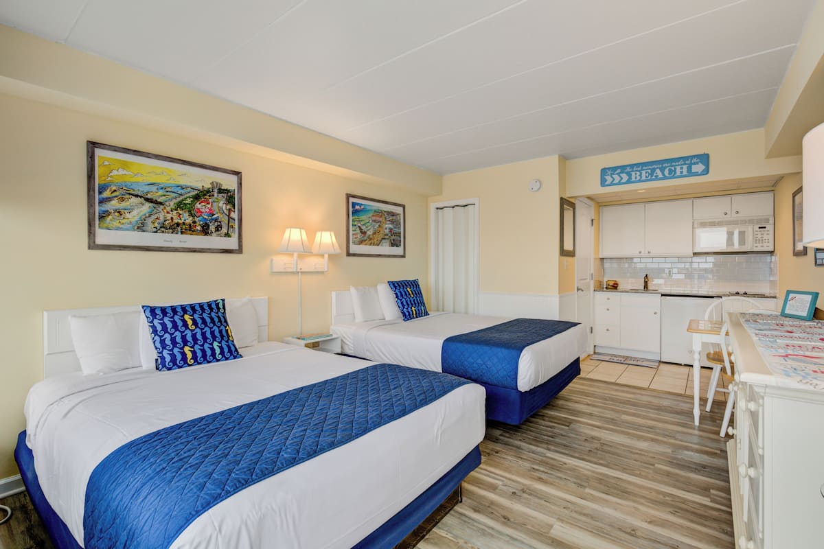 Habitación de hotel con dos camas, kitchenette e indicación del camino a la playa.