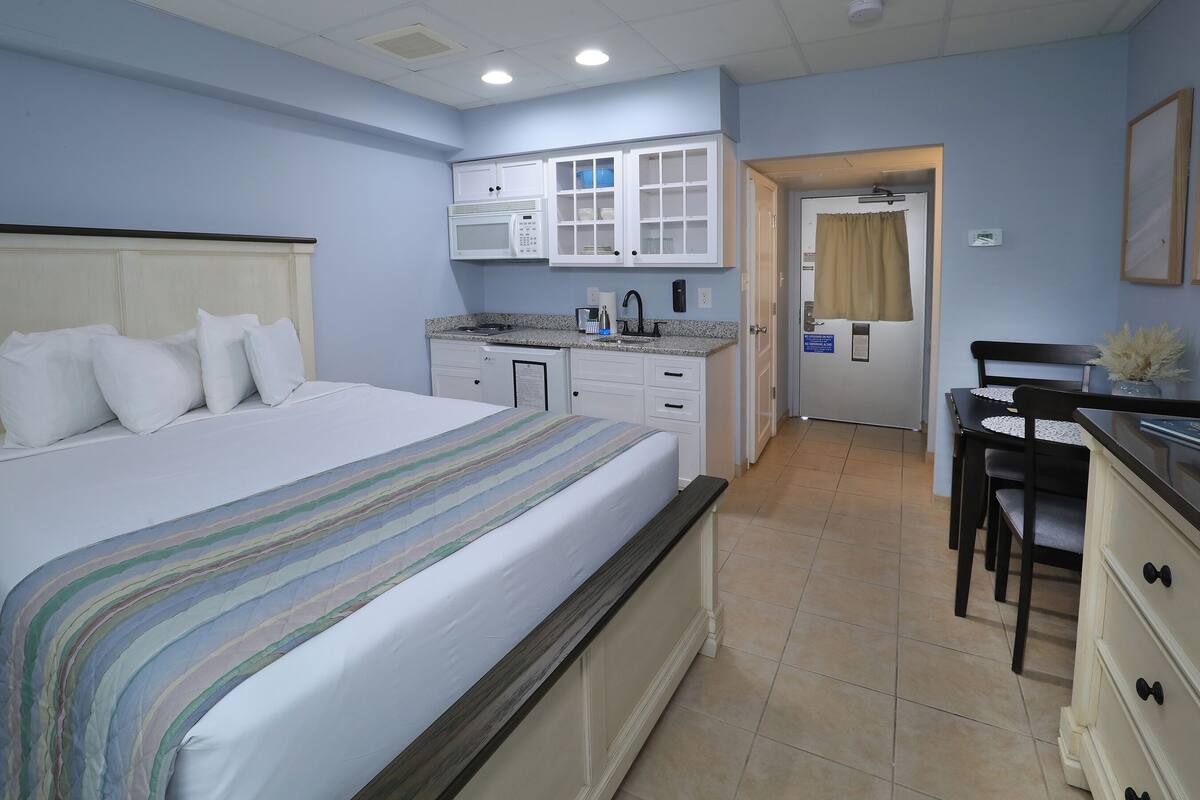 Una habitación de hotel con cama, kitchenette, zona de comedor y baño.
