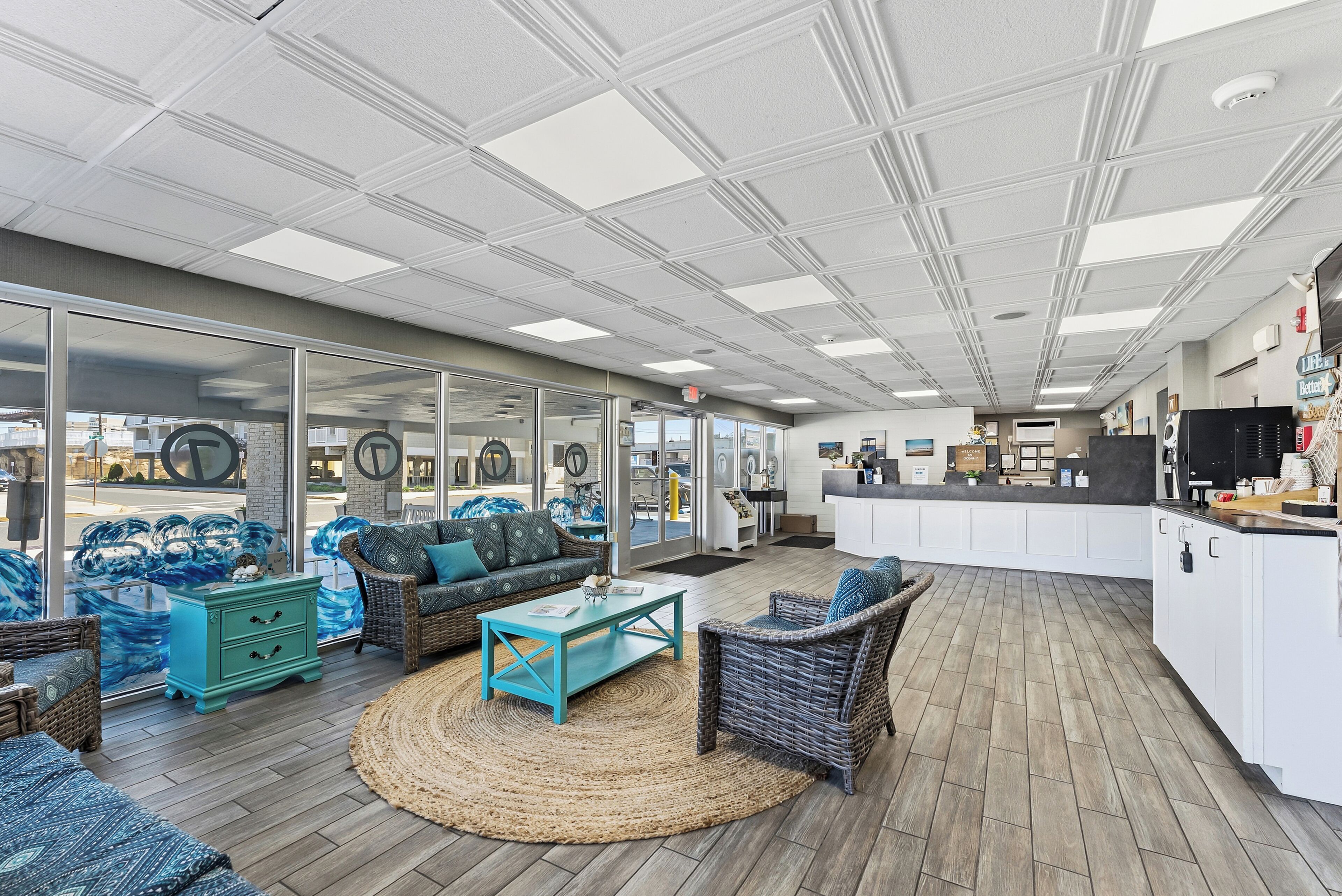 A spacious outdoor seating area with wicker furniture, a kitchen counter, and large windows.