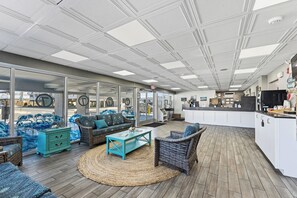 A spacious outdoor seating area with wicker furniture, a kitchen counter, and large windows. - Ocean 7 (Ocean City)