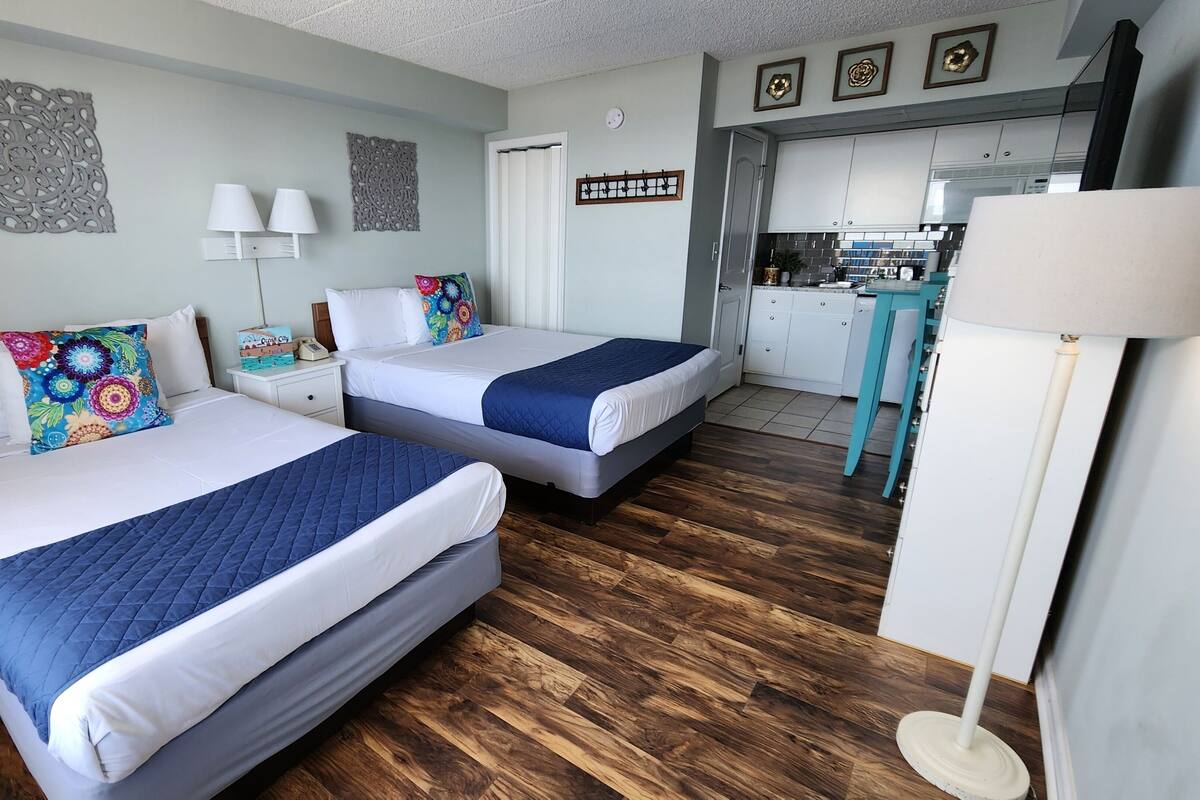 Una habitación de hotel con dos camas, un pequeño kitchenette y un baño.