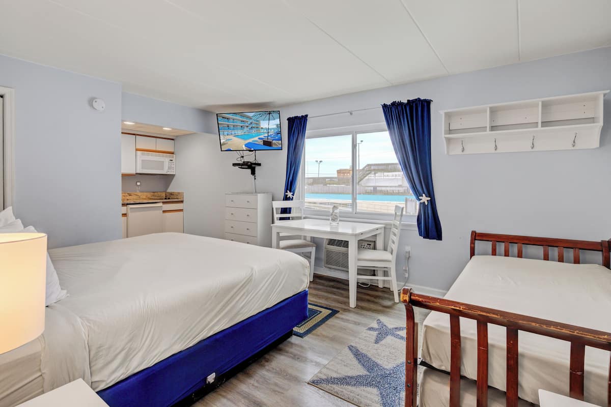 Una habitación de hotel con cama, escritorio, silla, televisor y vista a la piscina.