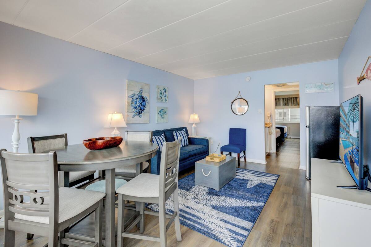 Una sala de estar con mesa de comedor, sofá azul y televisor.