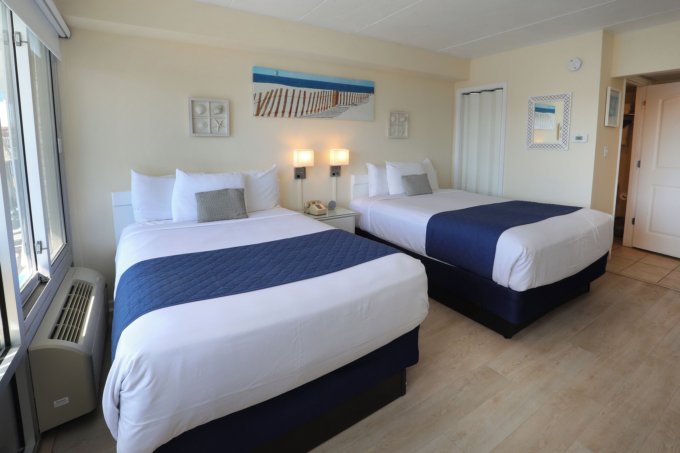A hotel room with two beds, a heater, and a window.