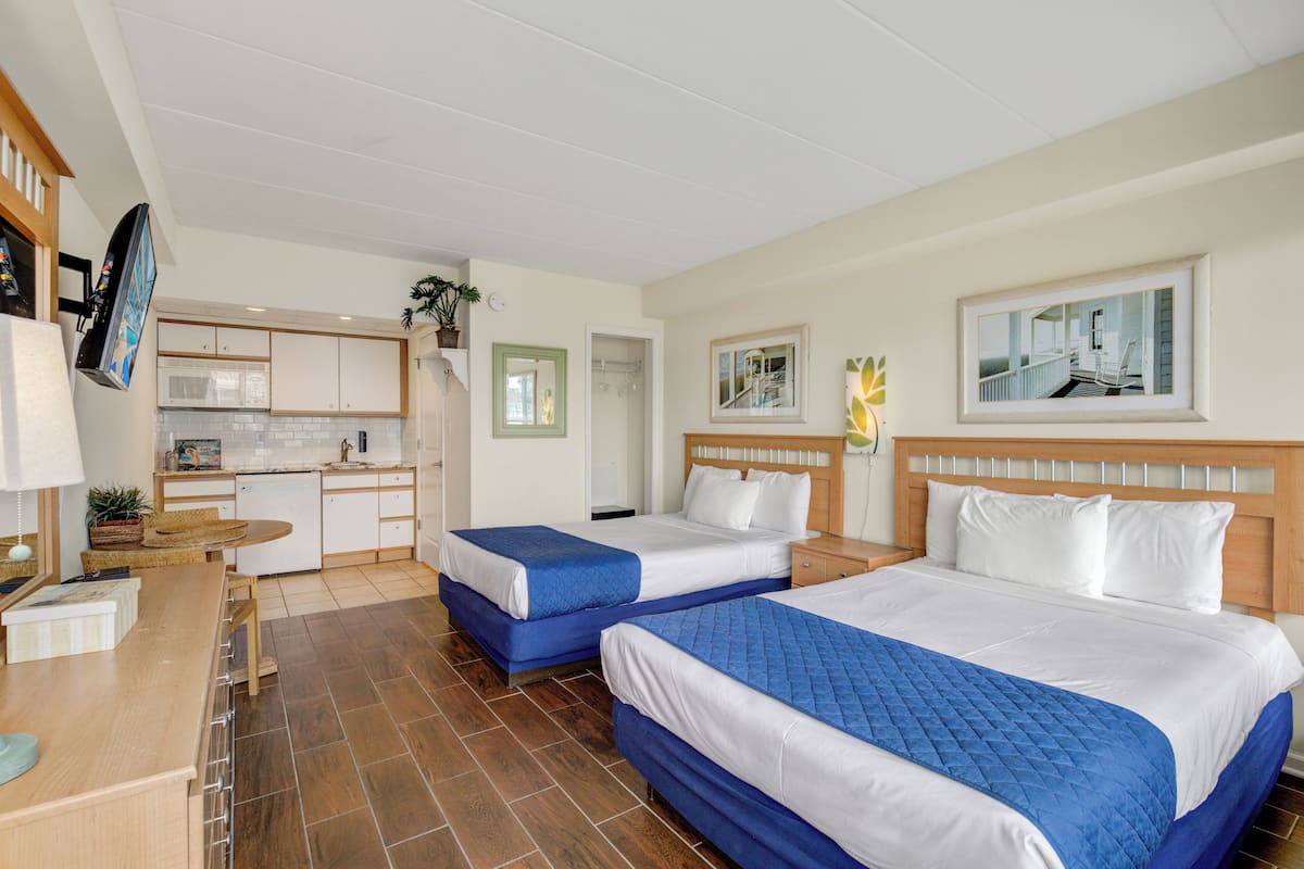 Habitación de hotel con dos camas, kitchenette, comedor y baño.