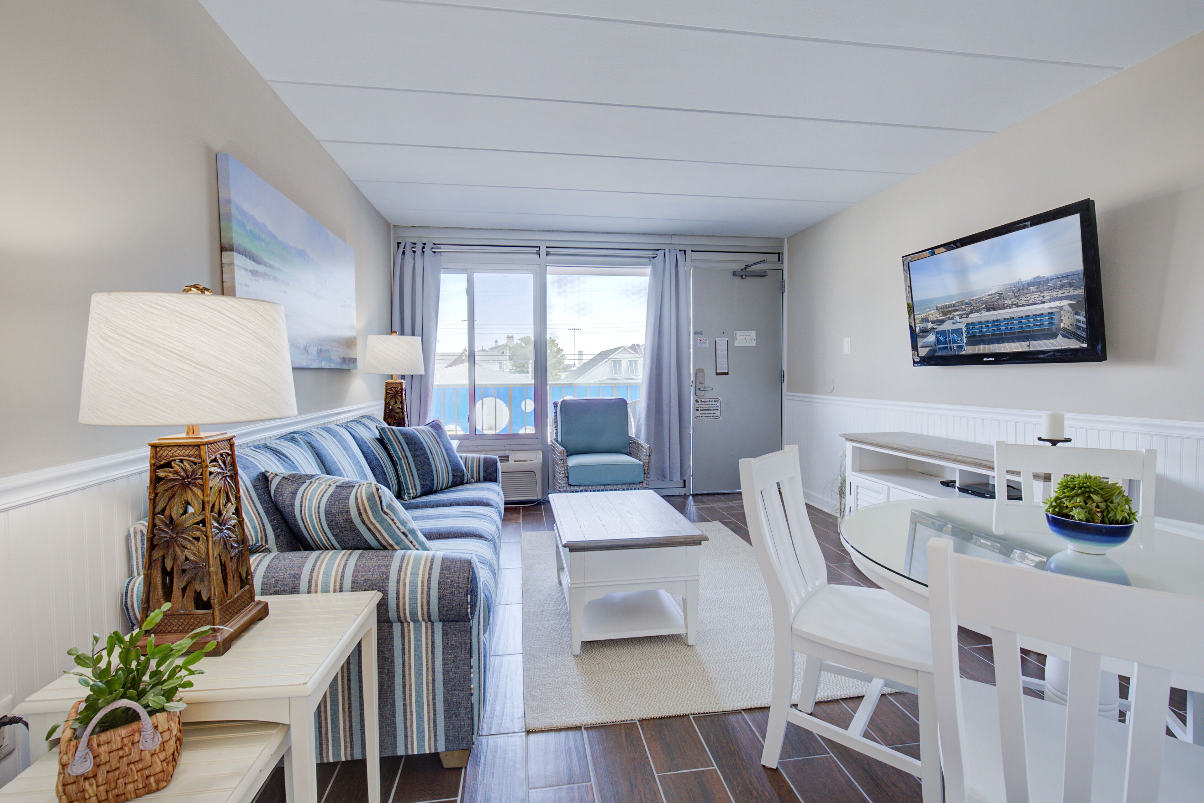 A modern living room with a sofa, a coffee table, a TV, and a dining area with chairs and a table.