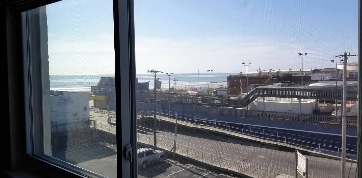 Vista desde una ventana con vistas al mar, un puente, una calle y edificios.