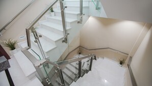 A modern staircase with glass railings and white steps, leading to an upper floor. - Hotel Borova (Korçë)