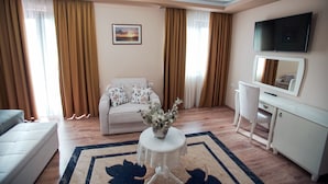 A living room with a sofa, a coffee table with a plant, a TV, and a desk with a mirror. - Hotel Borova (Korçë)
