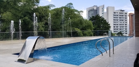 Una piscina al aire libre, sillones reclinables de piscina