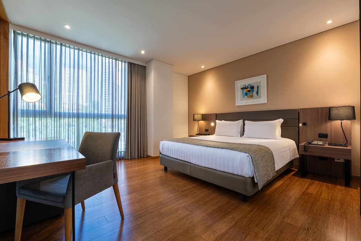 A modern hotel room with a large bed, a desk, and a chair.