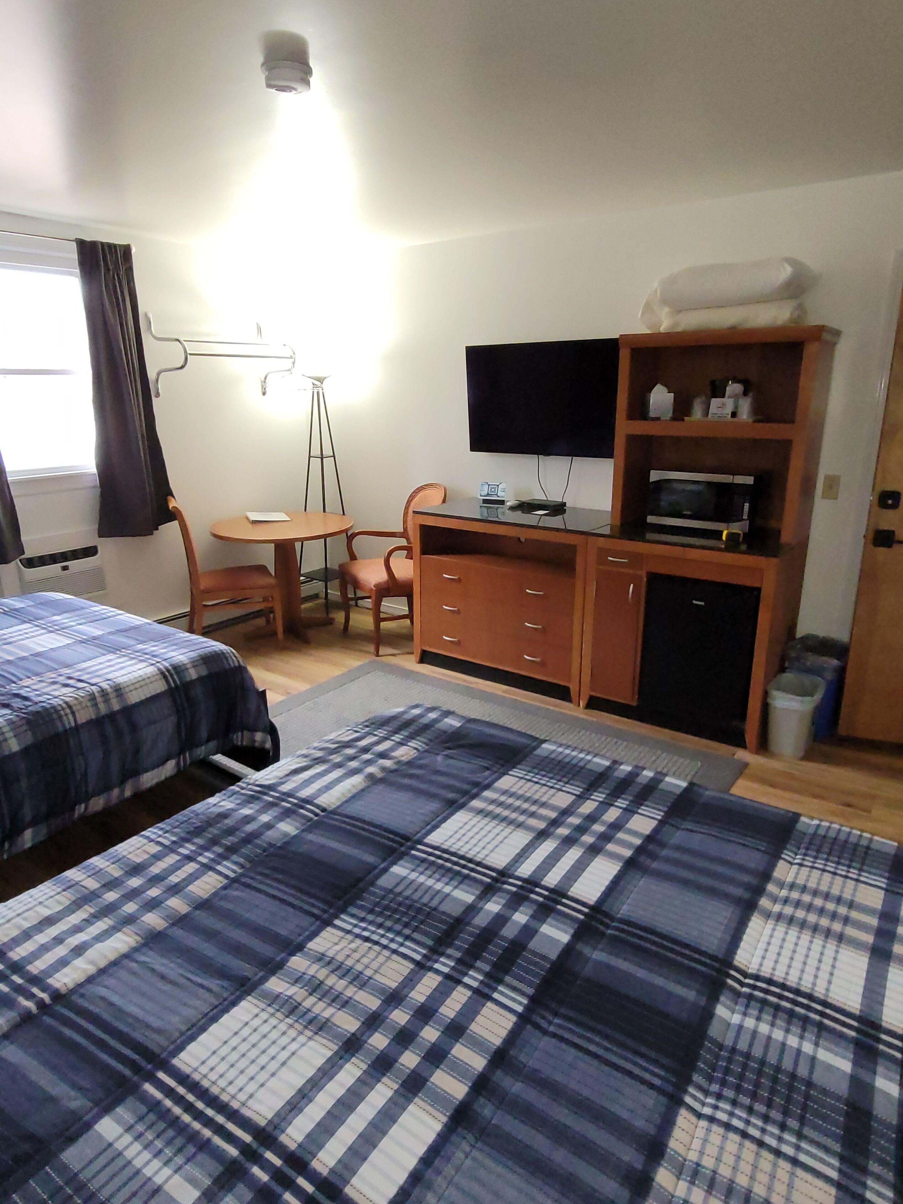 A hotel room with two beds, a desk, a chair, a television, and a microwave.