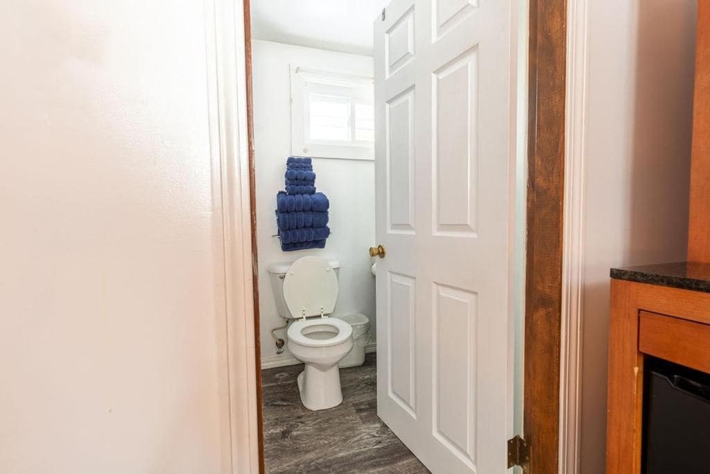 A bathroom with a white toilet, a blue towel stack, and a wooden cabinet.