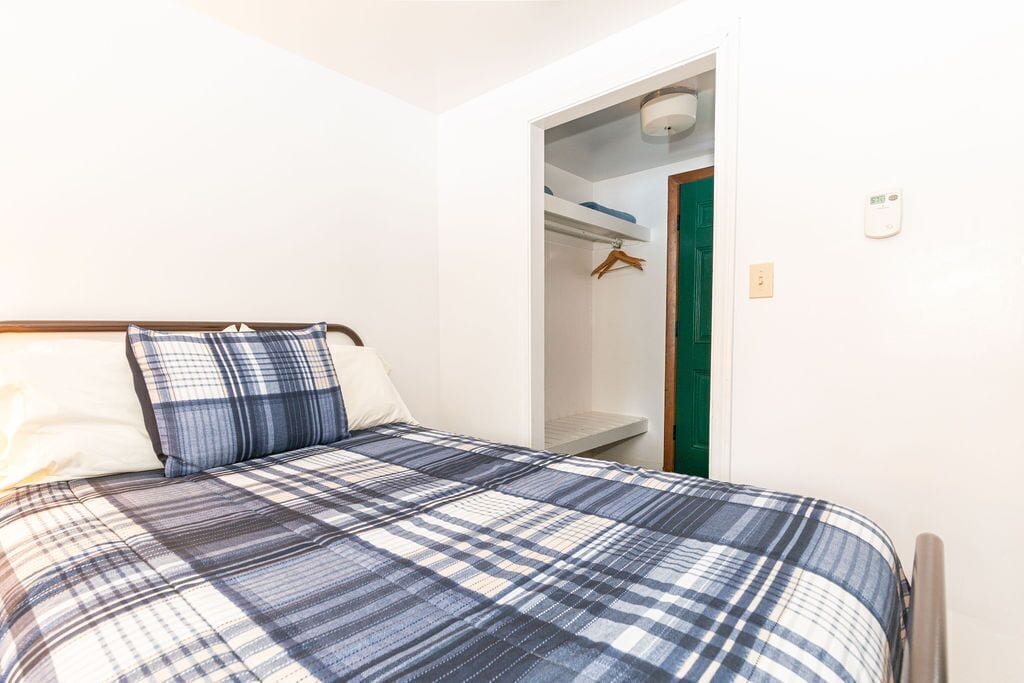 Ein Schlafzimmer mit einem Bett, einem Schrank und einer grünen Tür.