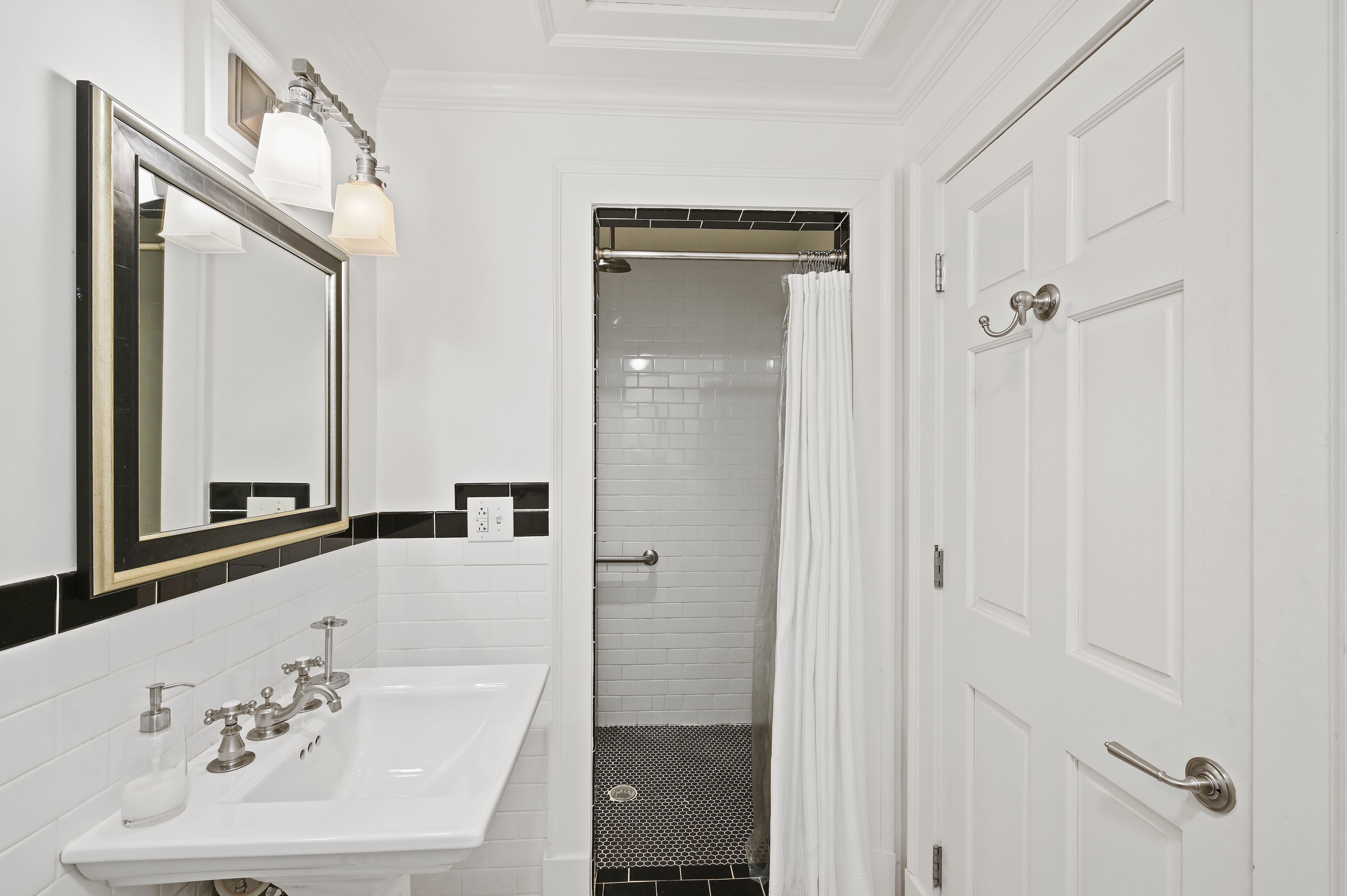 A bathroom with a white sink, mirror, and shower area.