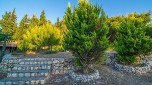 A stone staircase leading up to a stone wall, surrounded by evergreen trees. - Villa Elatia (Zakynthos)