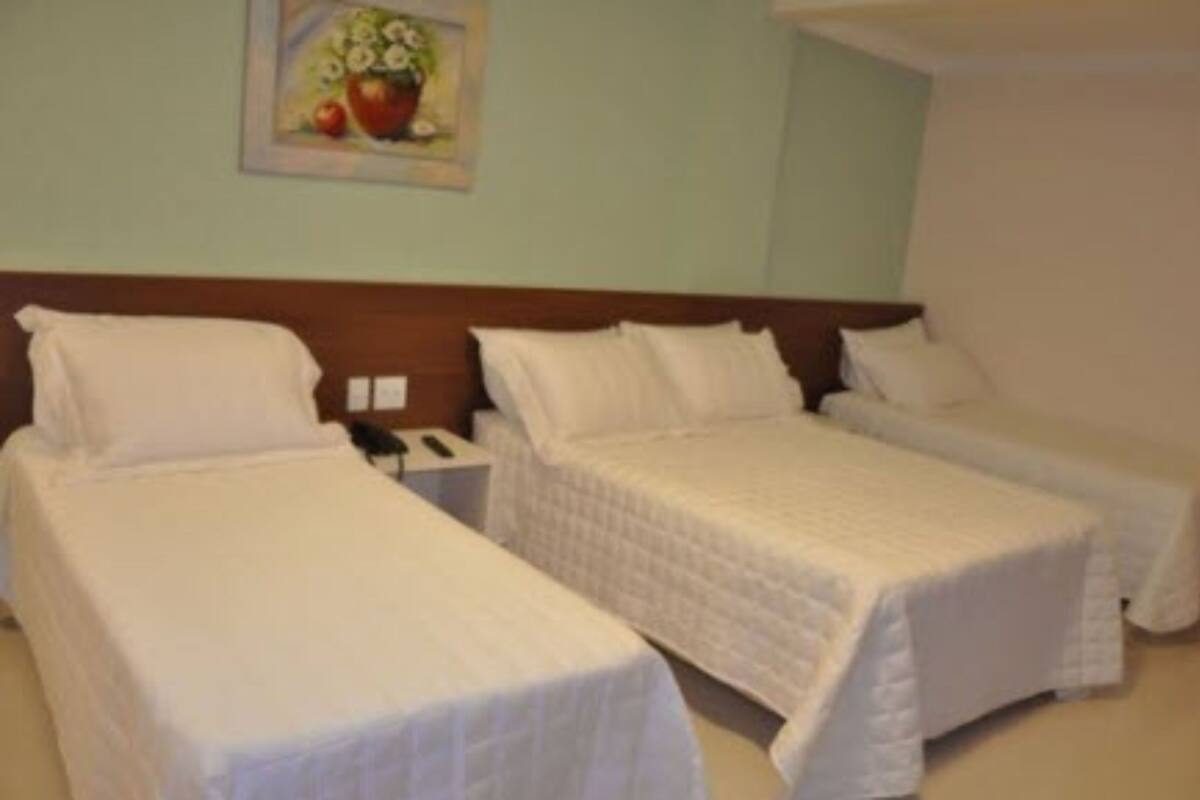 Una habitación de hotel con dos camas individuales, un cabecero de madera, una mesita de noche con teléfono y un cuadro en la pared.
