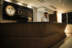 A hotel reception desk with a sign reading "HOTEL SARON ÁGUAS CLARAS". - Hotel Saron (Luziania)