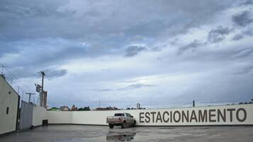 Un área de estacionamiento con una camioneta pickup, una pared con la palabra 'ESTACIONAMENTO' y el reflejo de la camioneta.