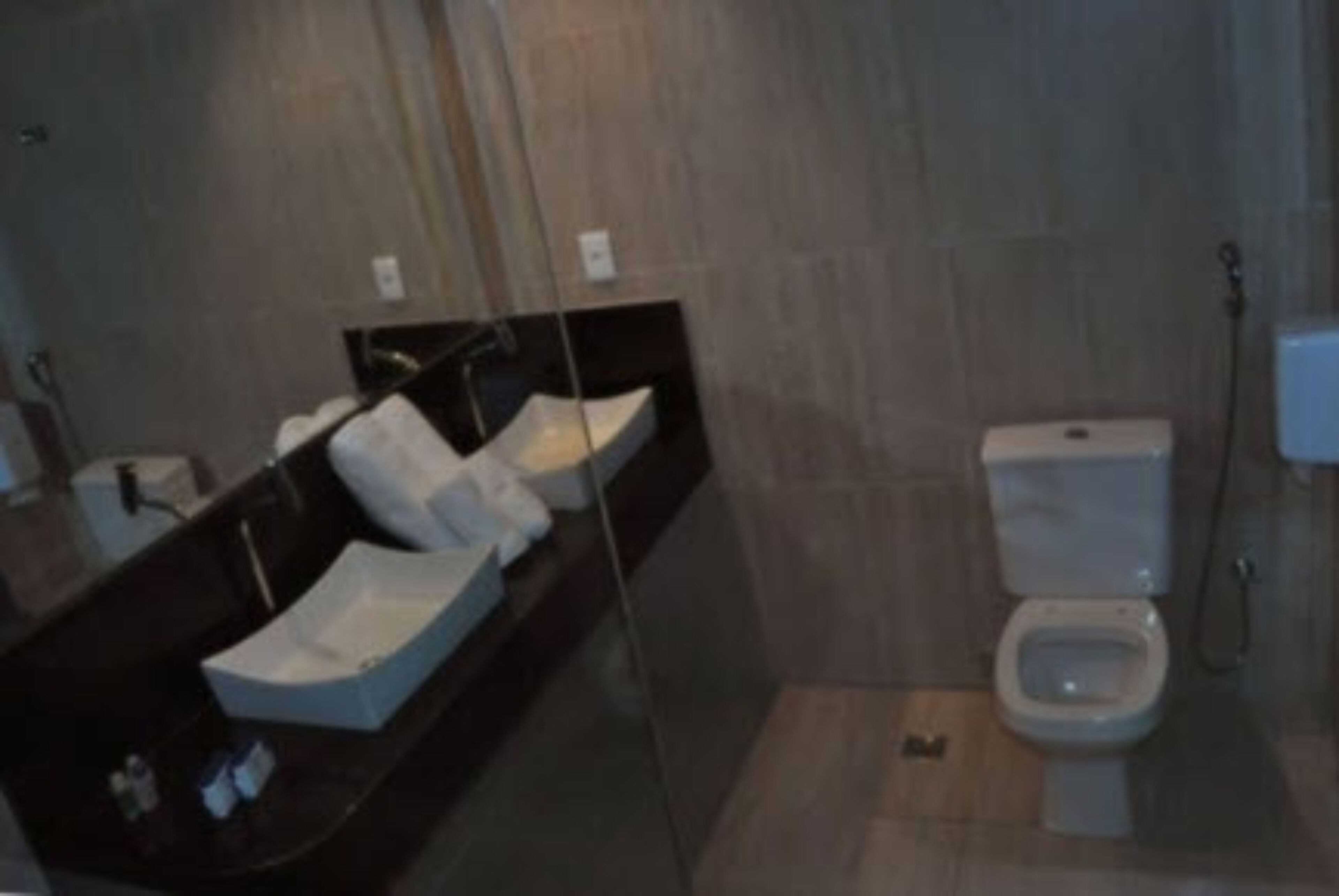 Un baño moderno con un espejo grande, encimera negra y un inodoro.