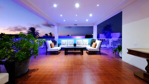 Un espace extérieur aménagé en terrasse, avec des sièges, des plantes en pot et une vue sur le coucher du soleil.