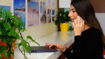 Una persona usando una computadora portátil en un escritorio con una planta en maceta y cuadros en la pared.
