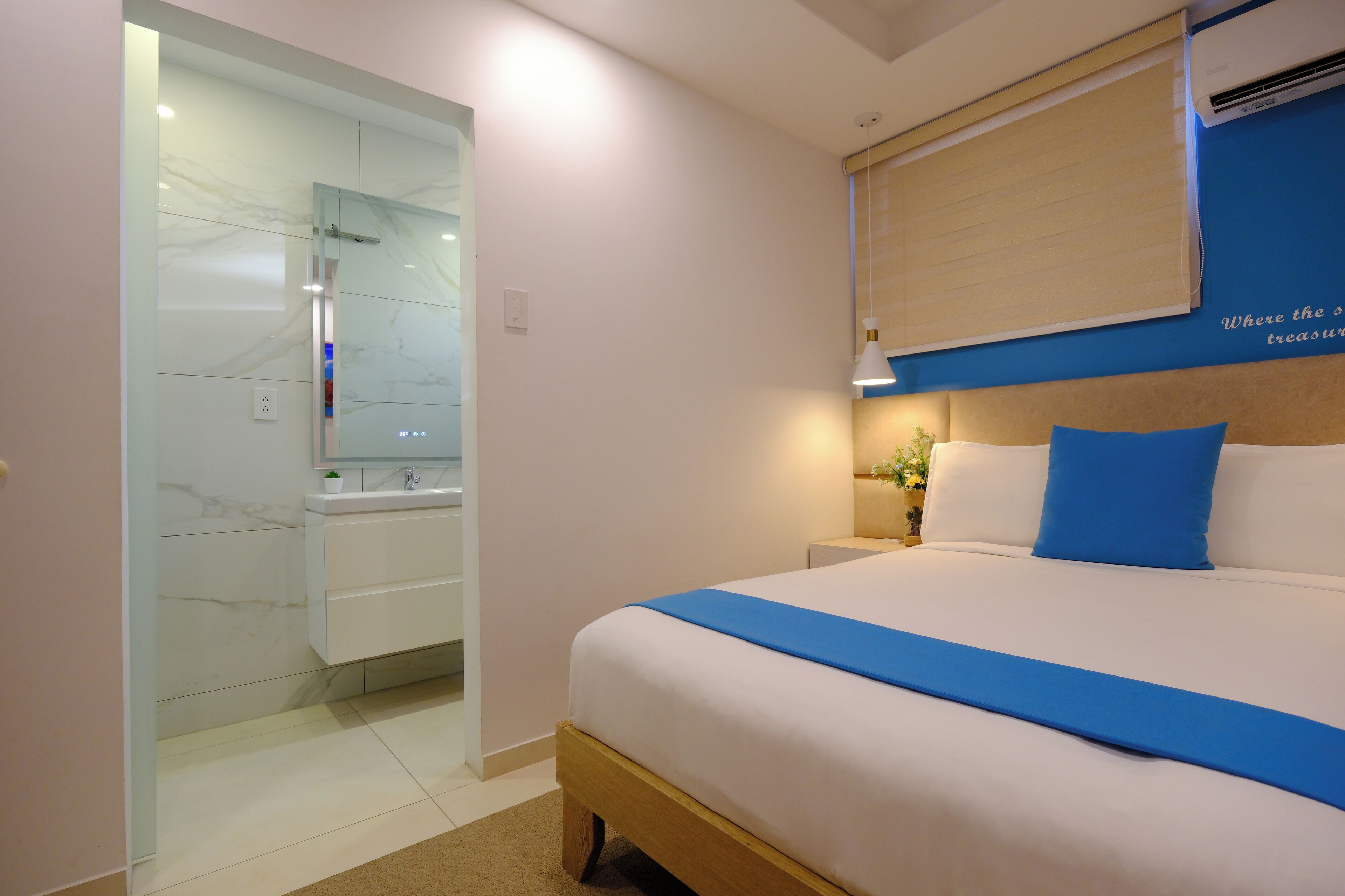 Ein modernes Hotelzimmer mit einem großen Bett, einem Nachttisch, einem Spiegel und einem Badezimmer mit Dusche und Waschbecken.
