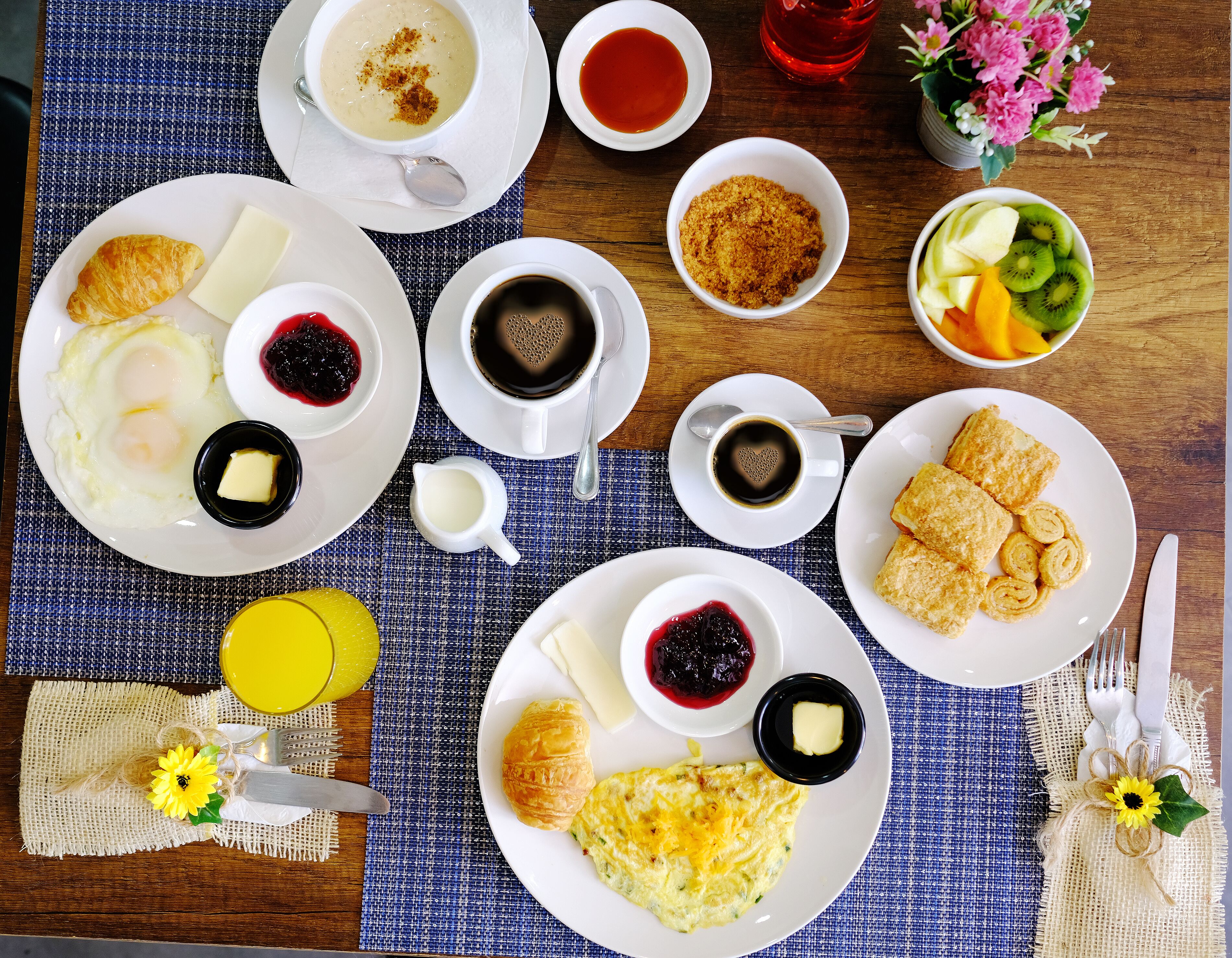 A breakfast table with plates of eggs, toast, and pastries, along with cups of coffee and tea.