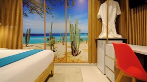 Une chambre à coucher comprenant un lit, un bureau, une chaise et une grande fenêtre donnant sur le désert et l’océan.