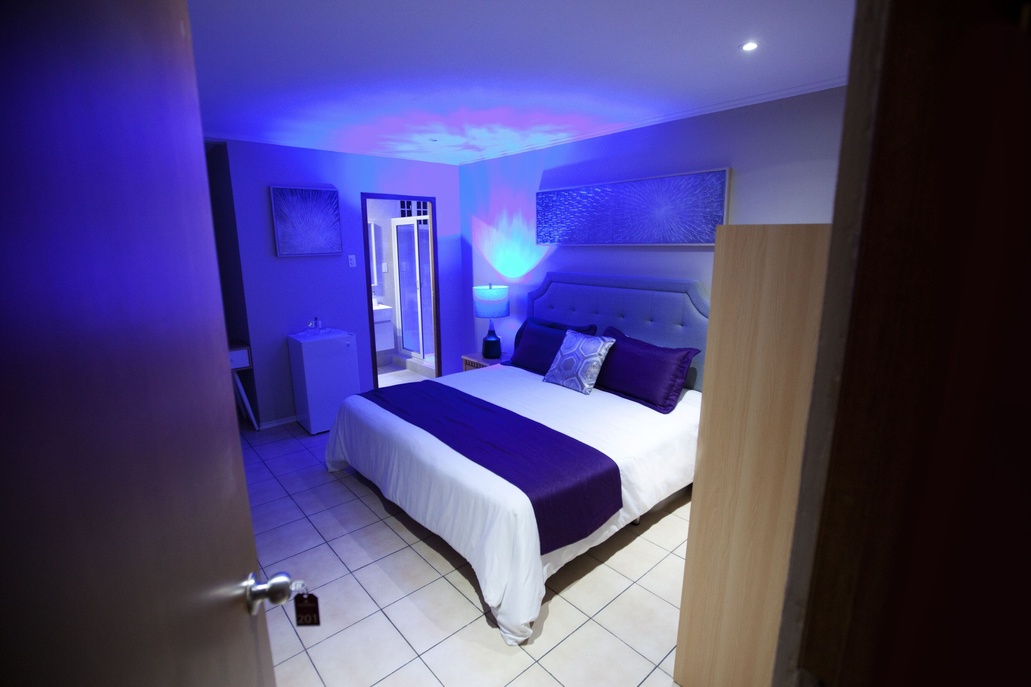 A bedroom with a bed, nightstands, a mirror, and a wall-mounted light fixture.