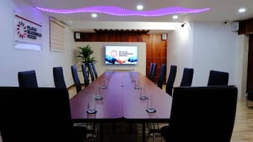 A conference room with a long table, chairs, a television screen, and a sign indicating it is the Playa Business Room.