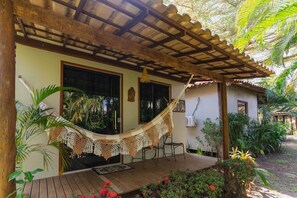 A covered porch with a hammock, wooden deck, and lush tropical plants. - Pousada Villa Mares (Maraú)