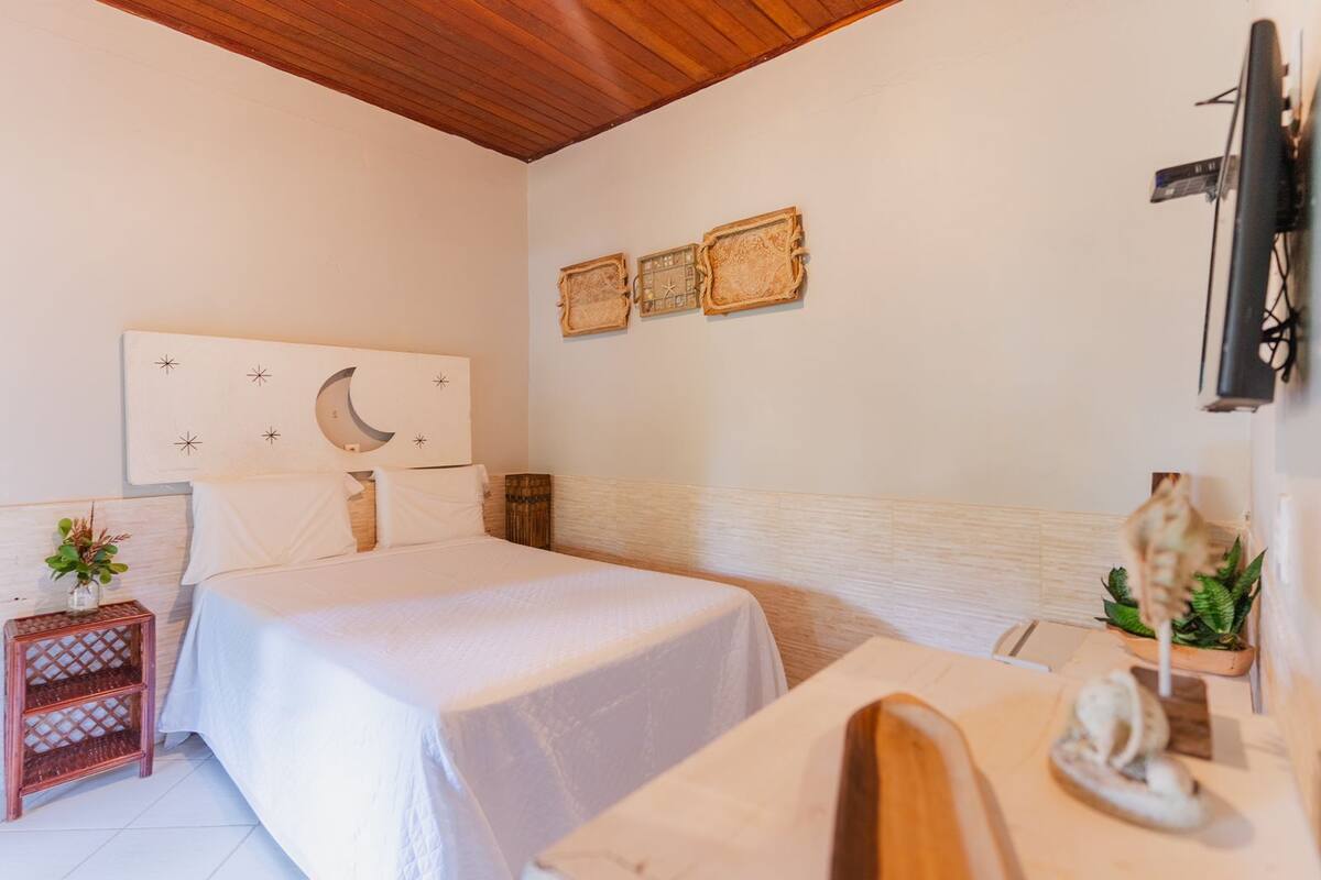 Une chambre à coucher comprenant un lit, une table de chevet, un téléviseur et des œuvres d’art décoratives au mur.