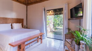 Un dormitorio con cama, un banco, un televisor y vistas al exterior.